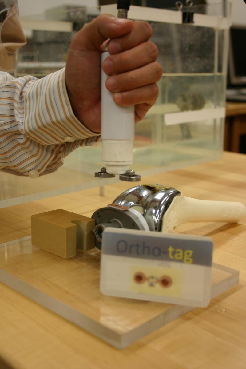 Ortho-Tag would be affixed to an orthopaedic implant and scanned via radio-frequency with a probe and RFID tag developed at Pitt. A card (foreground) would be available to patients with an existing implant.